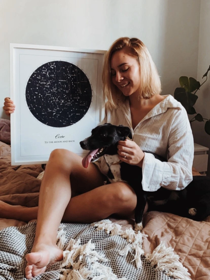 Egy boldog nő a születésnapi ajándékát tartja: egy egyedi csillagtérkép poszter a barátjától.