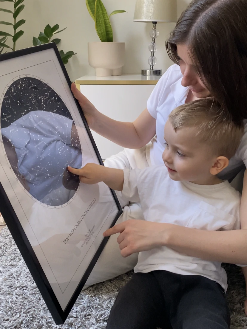 Egy anya a kisfiával nézegeti a születési csillagtérképet, ami egy megható ajándék az új szülőknek.